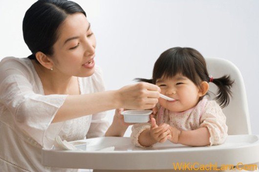 Asian mother feeding baby daughter